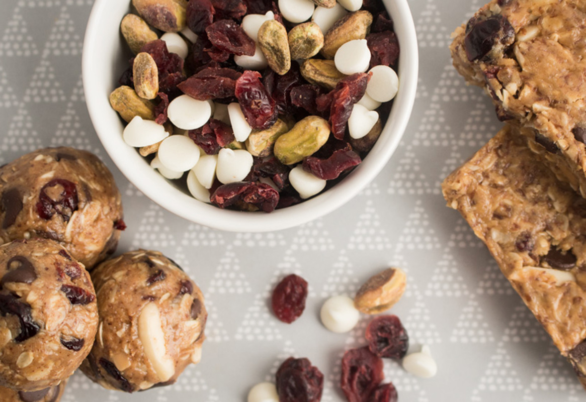 energy bites, granola bar, trail mix with cranberries, white chocolate chips, and pistachios on a platter